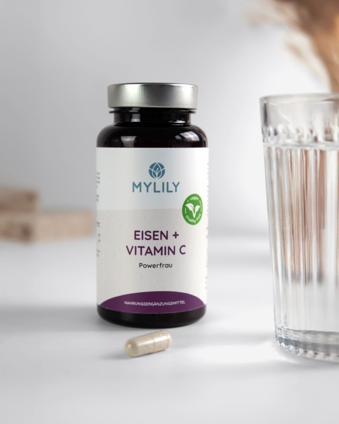 Bruine fles met capsules en glas. Opschrift: MYLILY, IJzer + Vitamine C, Powerfrau. Een capsule ernaast.