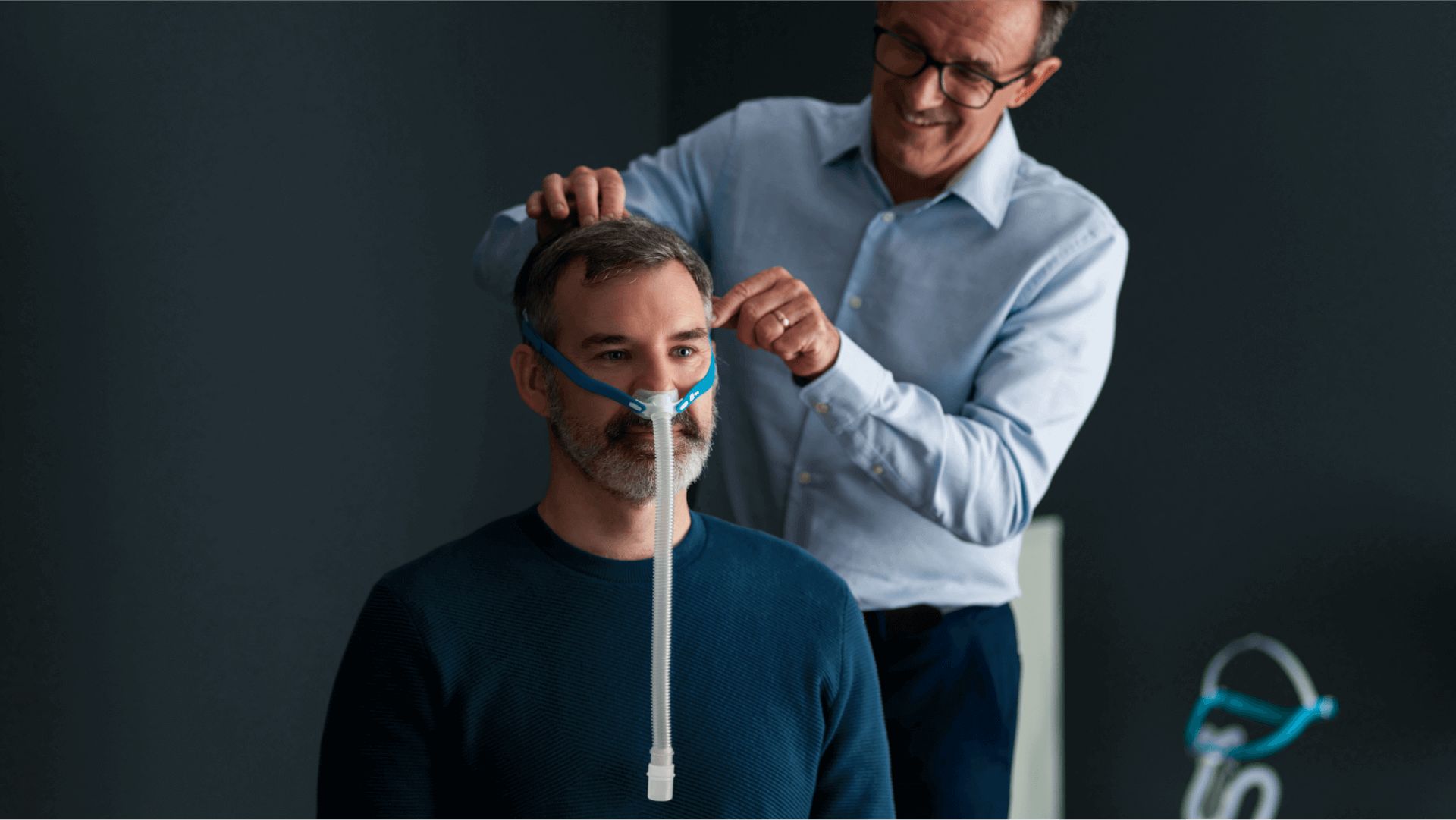 Man krijgt een F&P Nova Micro neusmasker aangemeten. Verstelbare hoofdband.