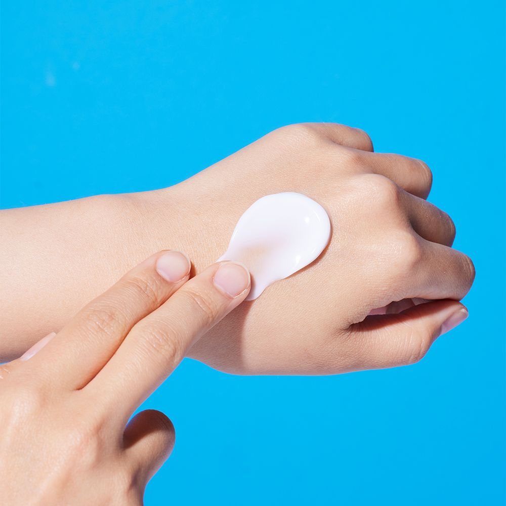 De la crème est appliquée sur une main pour montrer l'hydratation de la peau.