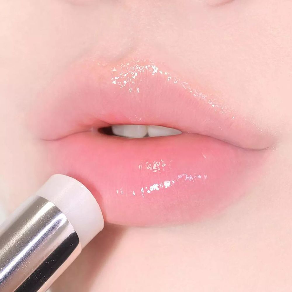 Gros plan sur des lèvres enduites de baume. Le baume est dans un stick argenté.
