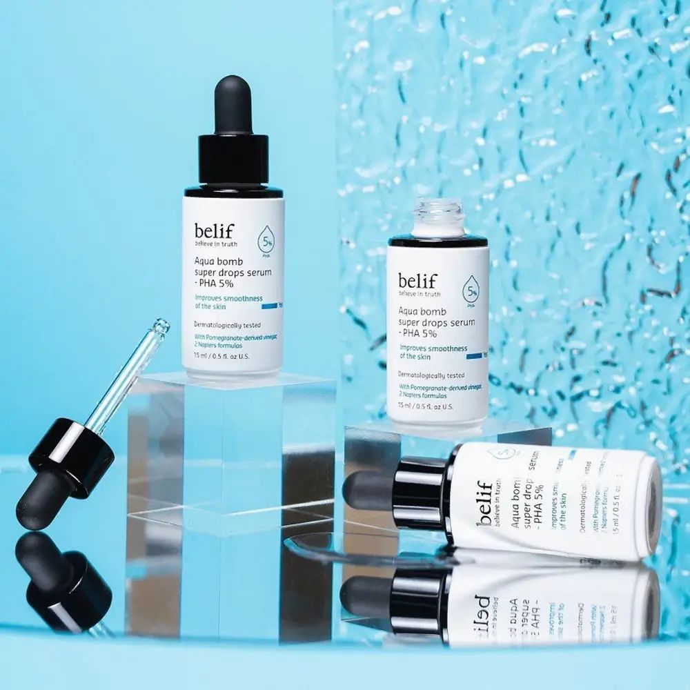 Verschillende serumflessen met zwarte dop en pipet. Opschrift: belif, Aqua bomb super drops serum - PHA 5%.
