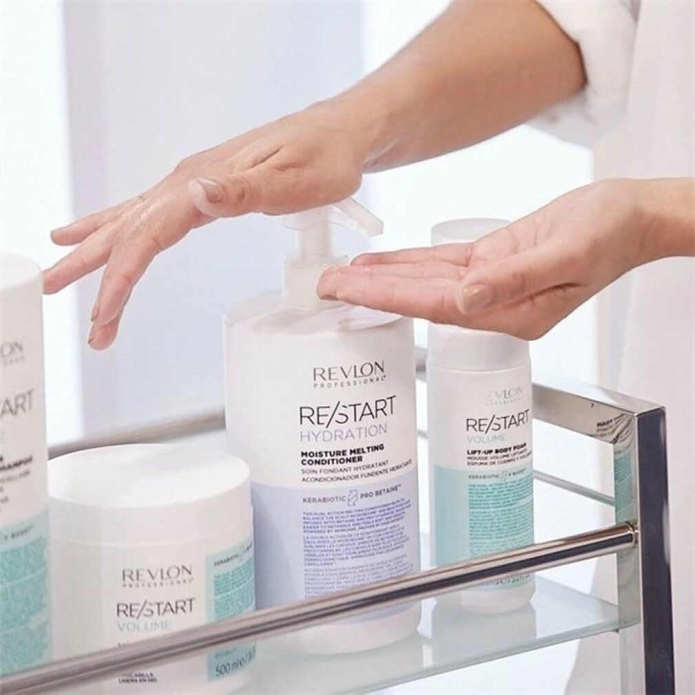 Handen boven een selectie Revlon Re-Start producten. Bevat conditioner, shampoo en andere producten op een kar.