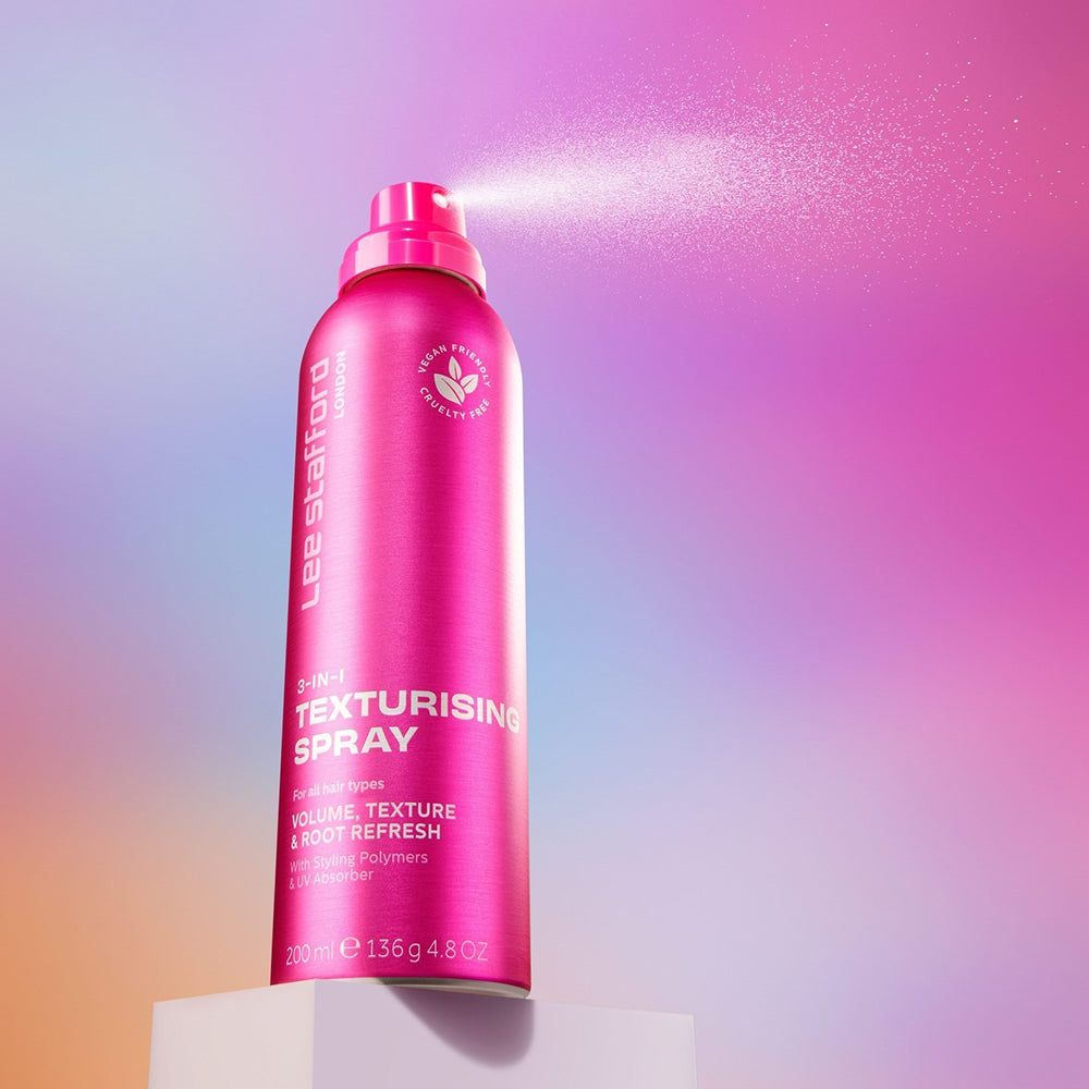 Lee Stafford 3-in-1 Texturising Spray, rose, brumisation, sur un cube blanc.