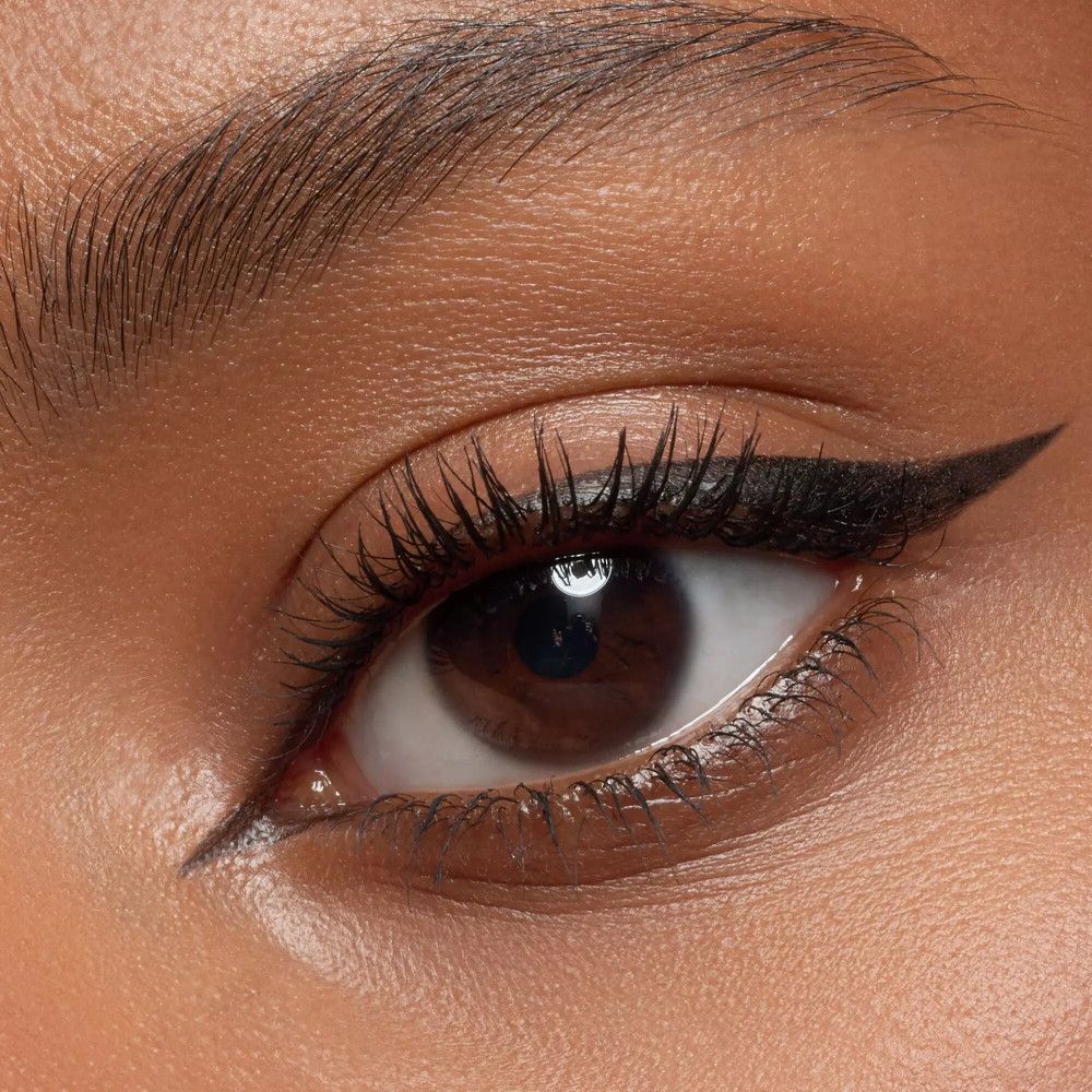 Œil avec trait d'eye-liner noir. Cils mis en valeur. Teint: brun.