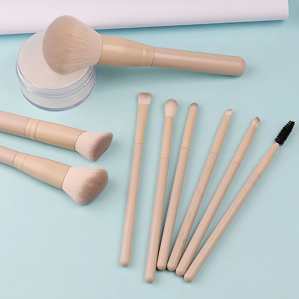 Un ensemble de huit pinceaux de maquillage avec des manches beige clair et des poils clairs. Un pinceau est un gros pinceau à poudre, les autres sont de plus petits pinceaux pour les yeux et une brosse à mascara.