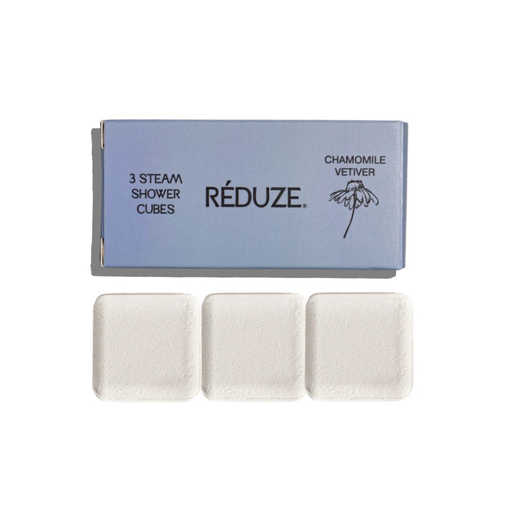 Drie vierkante doucheblokjes en een doos. Op de doos staat RÉDUZE en Kamille & Vetiver.