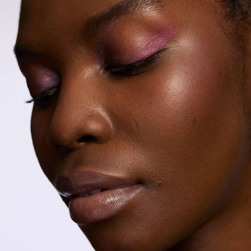 Gros plan d'un visage avec fard à paupières rose. Yeux fermés.