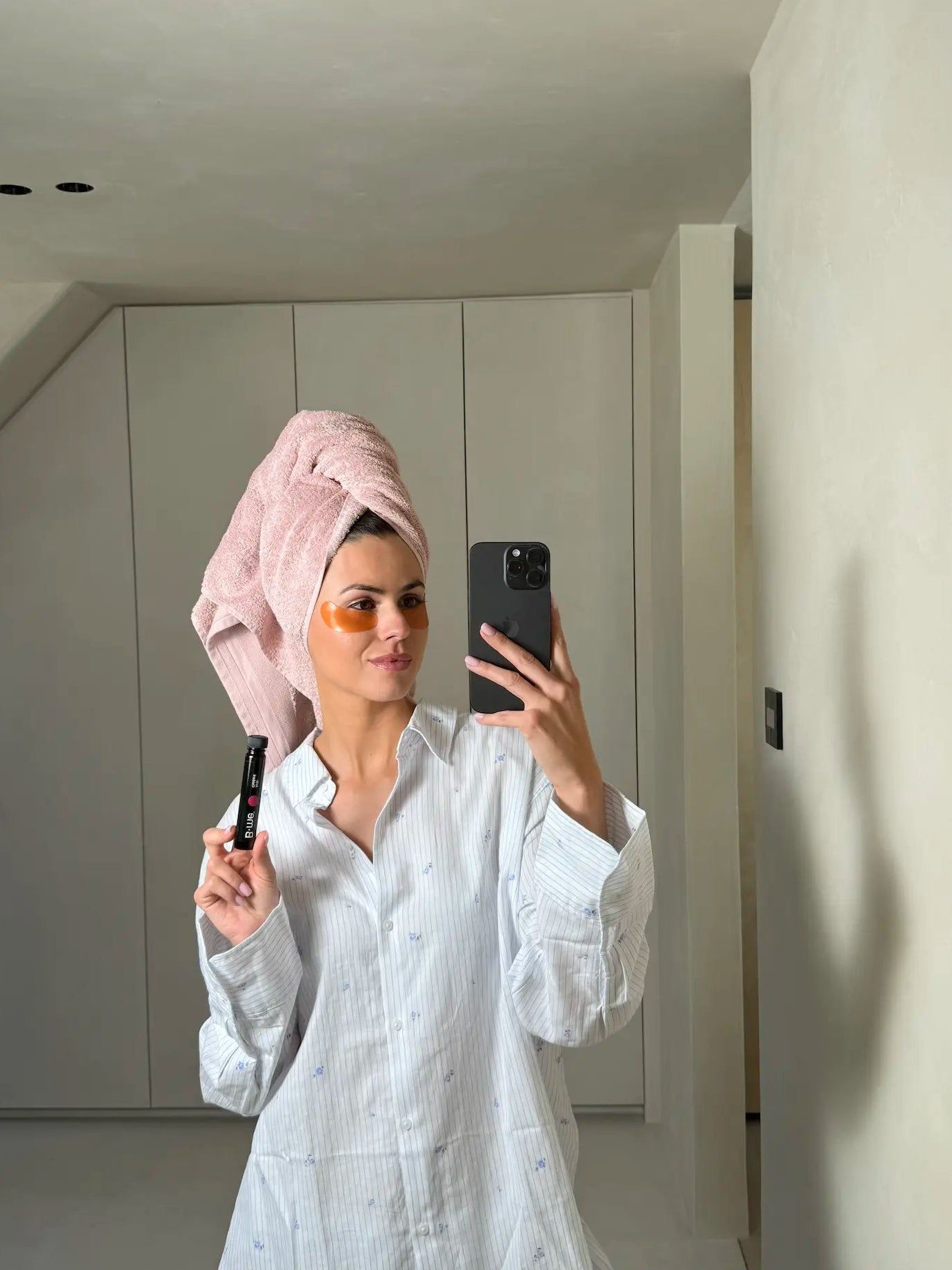 Vrouw met handdoek op haar hoofd houdt B.me® Anti-Oxidant vast. Ze maakt een selfie. Het product is in een ampul.