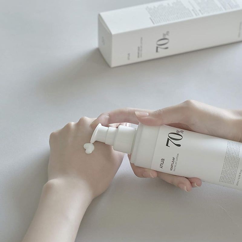 Handen die lotion uit een witte fles persen. Opschrift: Anua, Heartleaf 70% Daily Releaf Lotion, 70%.