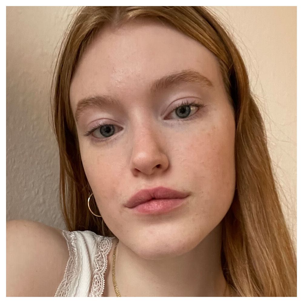 Gros plan d'un visage avec imperfections. Teint: clair. Yeux: bleus. Lèvres: roses. Cheveux: roux.