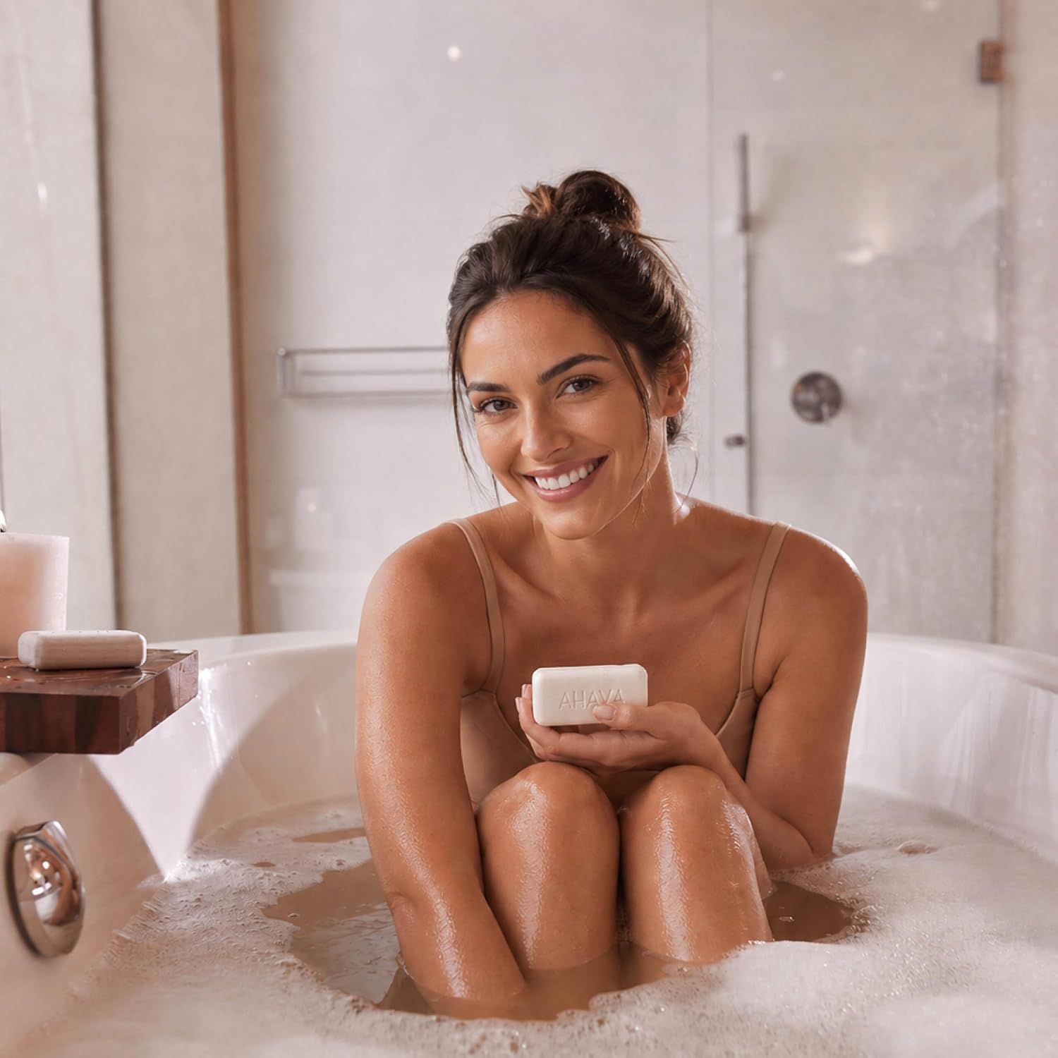 Vrouw in bubbelbad houdt witte zeep vast.