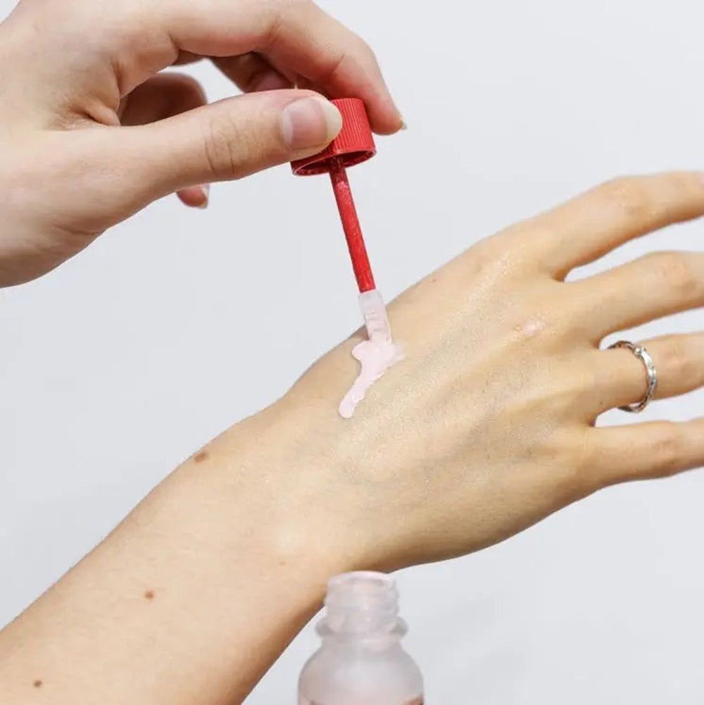 Applicateur avec poudre rose appliquée sur une main.