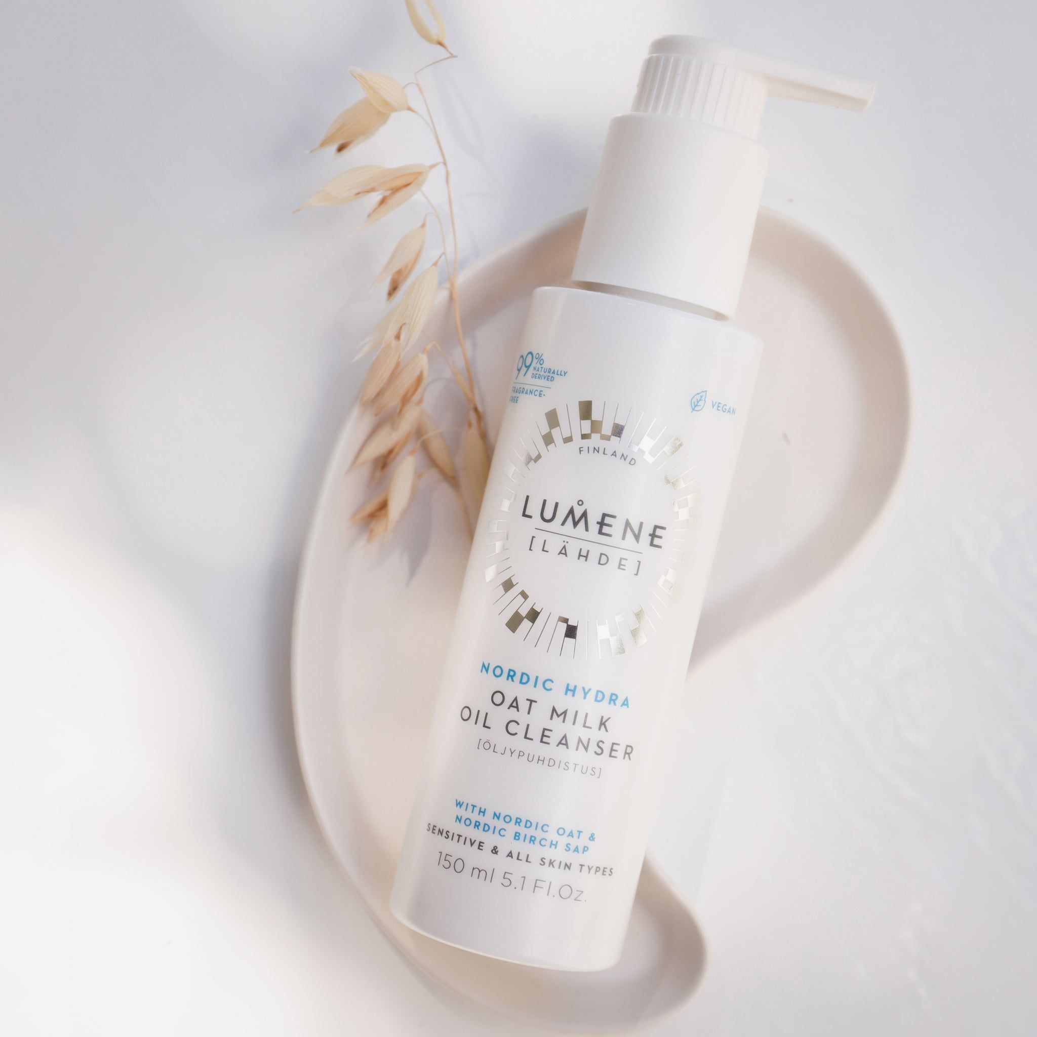 Witte fles met pomp op een dienblad. Opschrift: Lumene Nordic Hydra Oat Milk Oil Cleanser. Met havermelk. 99% natuurlijk.