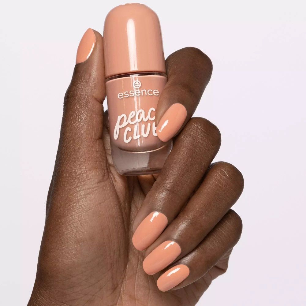 Main avec ongles vernis et flacon de vernis. Vernis rose. Marque et nom du produit visibles.