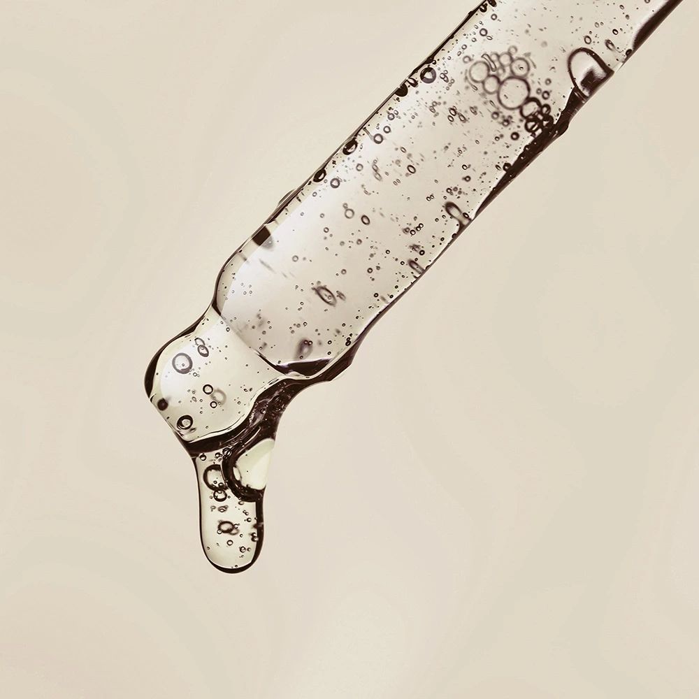 Close-up van een pipet met serum. Heldere vloeistof met bellen. Druppelvorming.