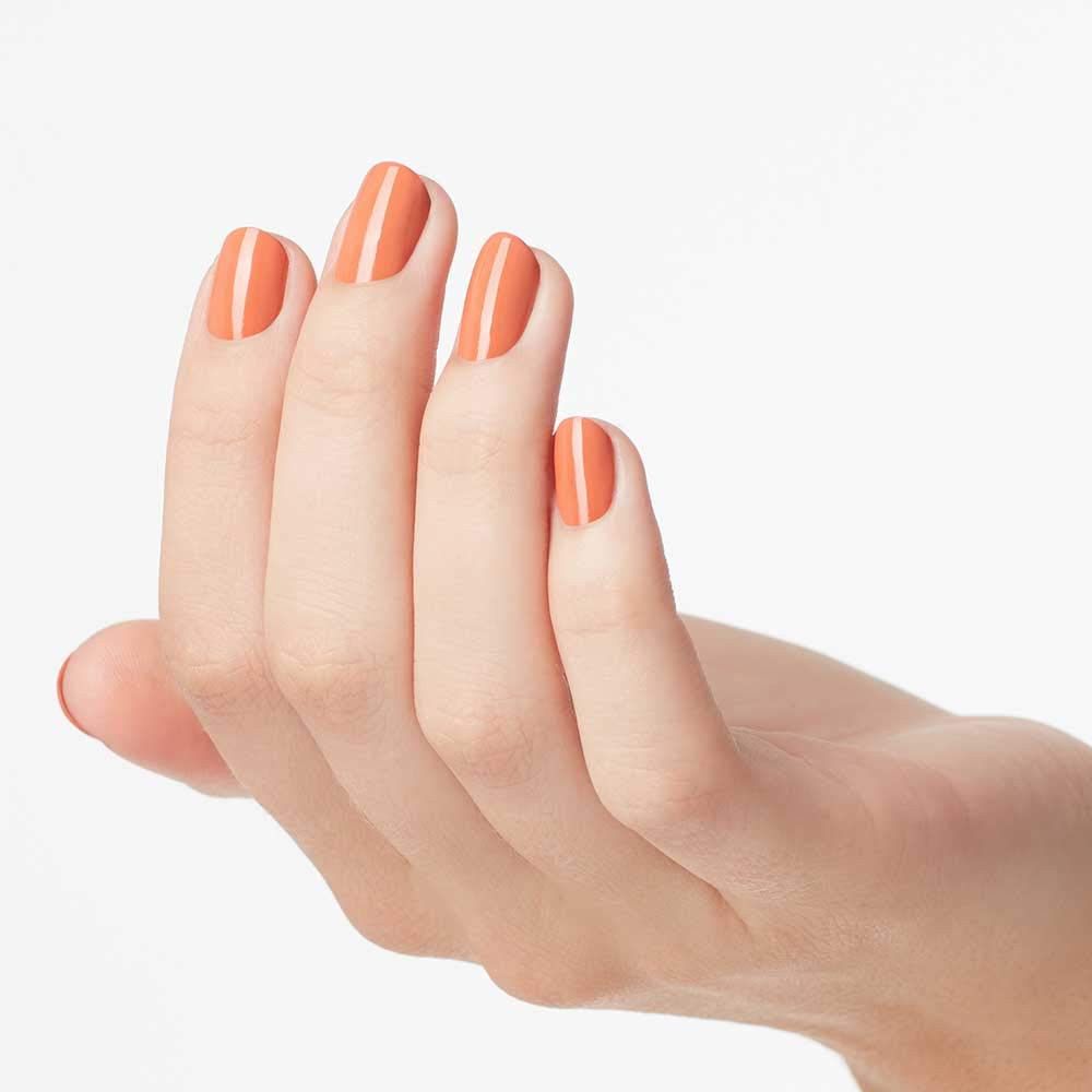 Hand met gelakte nagels. De nagels zijn gelakt met oranje nagellak.