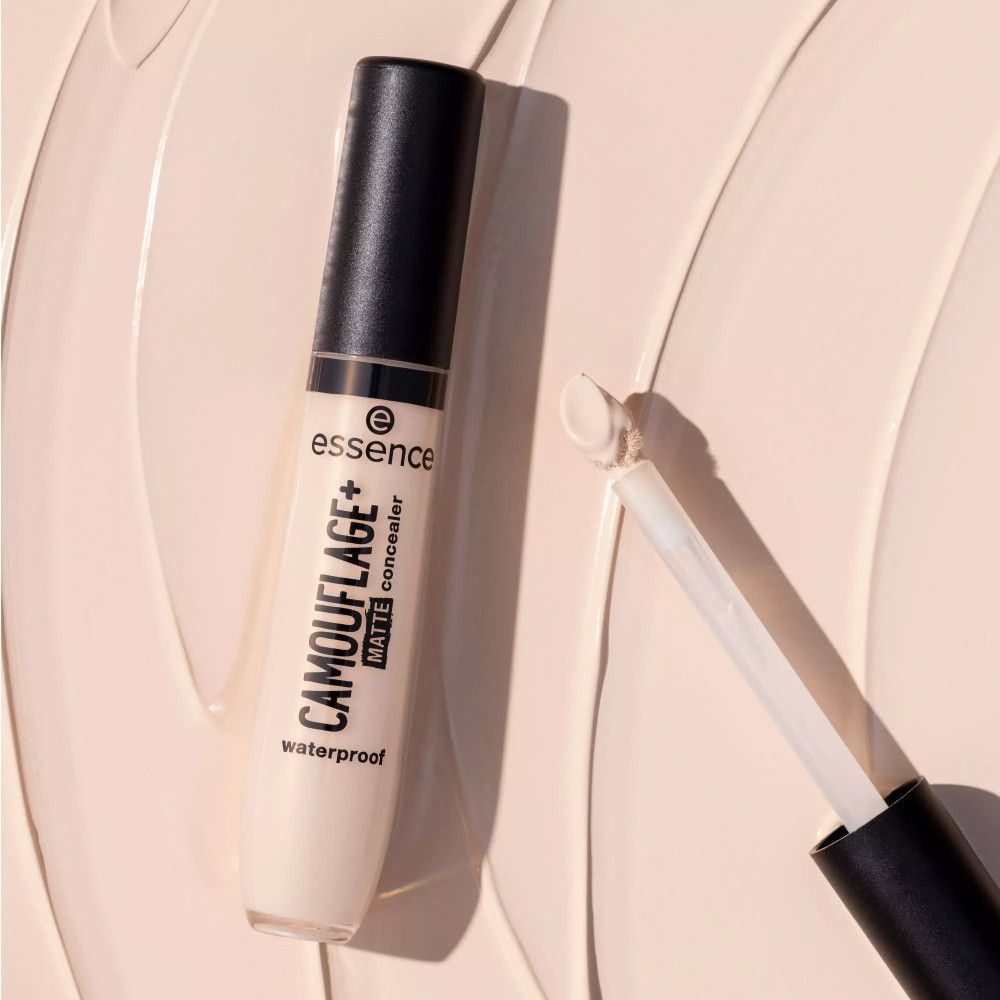 Tube de correcteur avec applicateur. Inscription: CAMOUFLAGE+ matte concealer waterproof. Marque: essence. Fond: traits de correcteur.