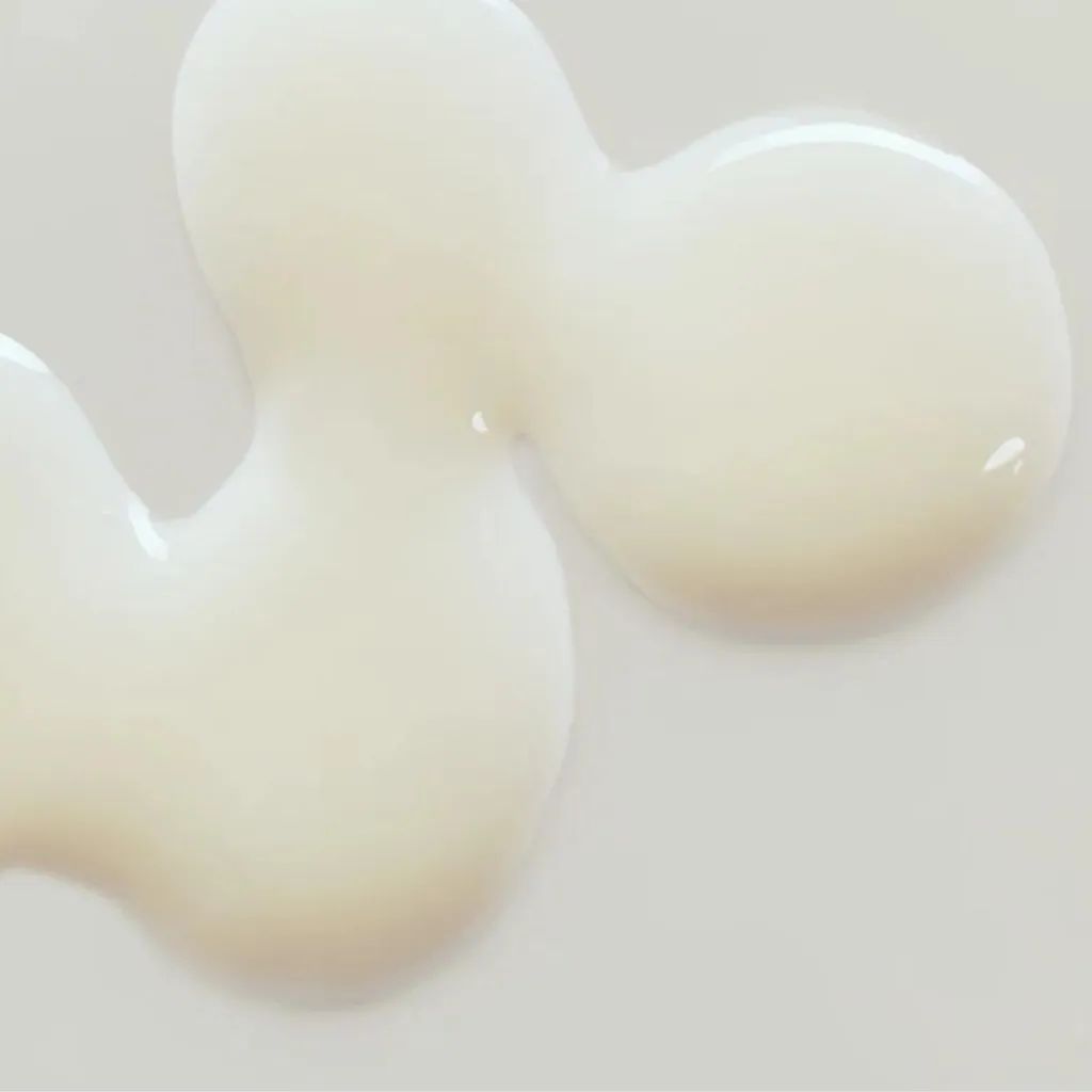 Close-up van serum op witte achtergrond. Crèmekleurige serumdruppels in onregelmatige vorm. Glad, glanzend oppervlak.