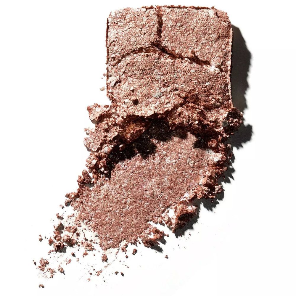 Fard à paupières doré cassé avec paillettes sur fond blanc. Texture friable.