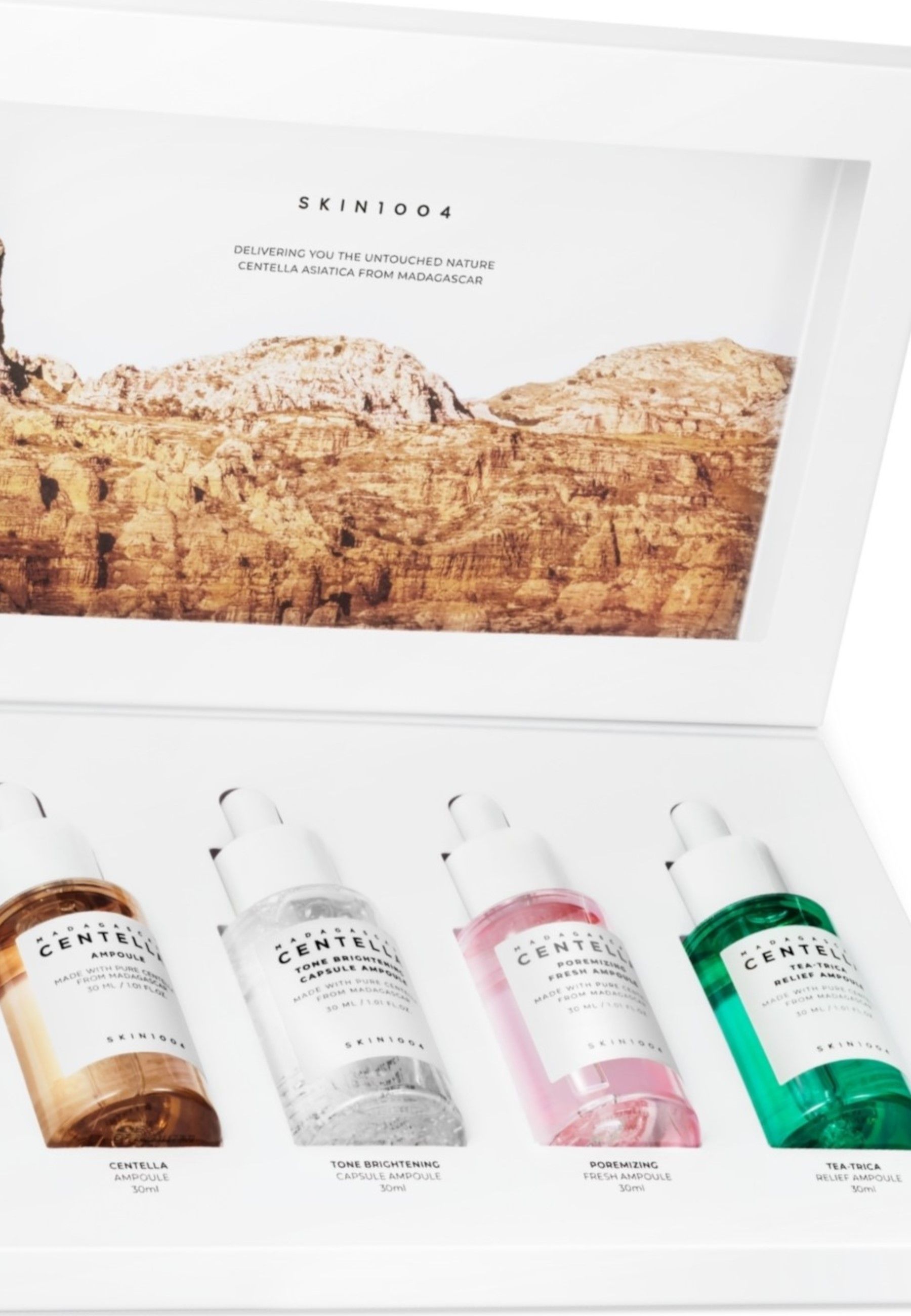 Close-up van de geopende witte doos met vier ampullen. Elke ampul heeft een andere kleur en opschrift. Landschapsachtergrond.