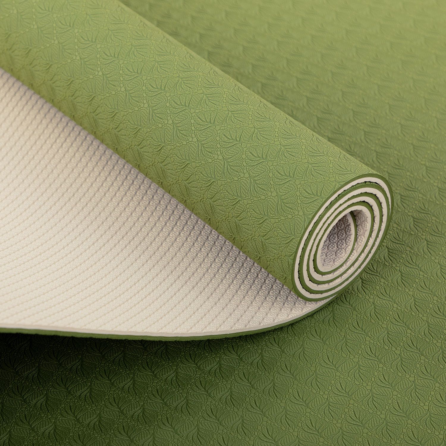 Opgrolde yogamat. Groene bovenkant met patroon, crèmekleurige onderkant. Opgrold, detailweergave.