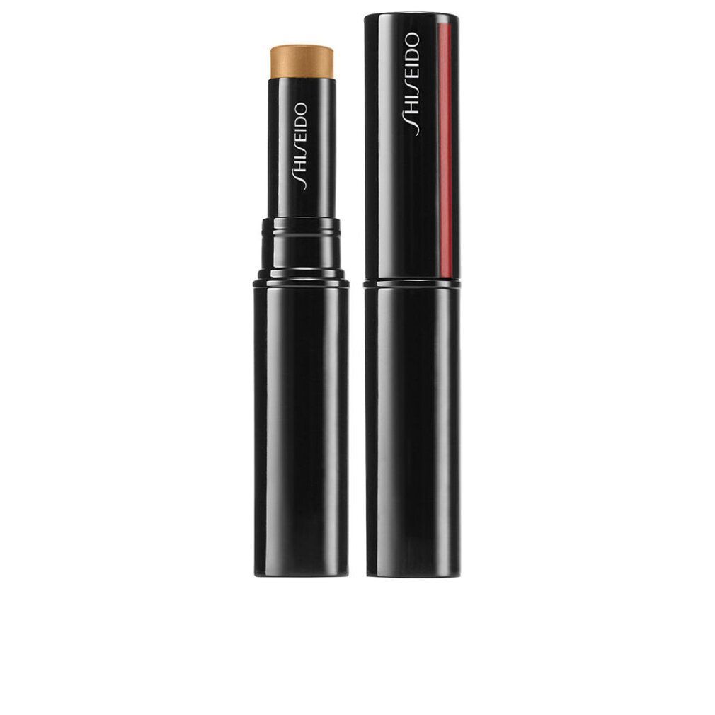 Stick correcteur, bleu foncé avec rayure rouge. Capuchon à côté. Nom du produit et marque: SHISEIDO. Stick couleur crème.