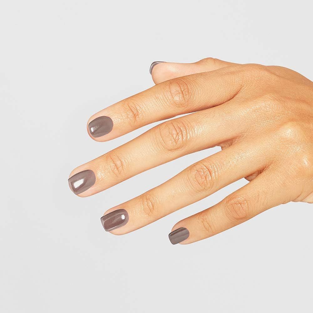 Main avec ongles vernis dans une teinte gris-brun. Les ongles sont brillants.