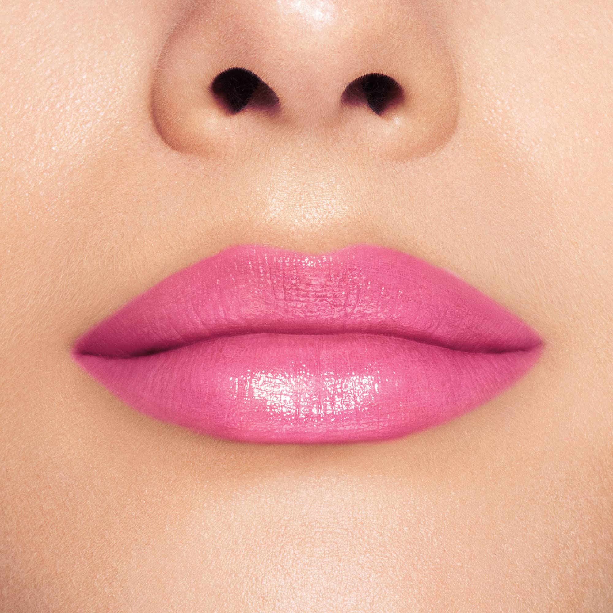 Gros plan sur des lèvres recouvertes de baume à lèvres rose. Les lèvres sont brillantes.