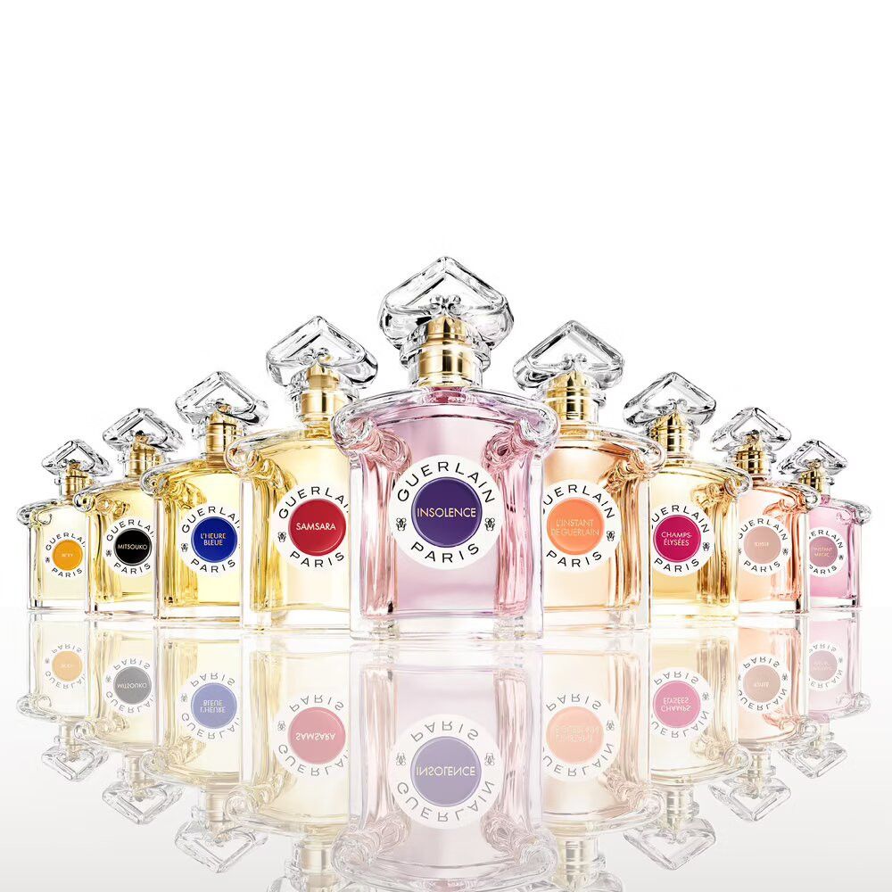 Plusieurs flacons en verre. Étiquettes avec différents noms. Bouchons dorés. Vaporisateurs transparents. Reflet.