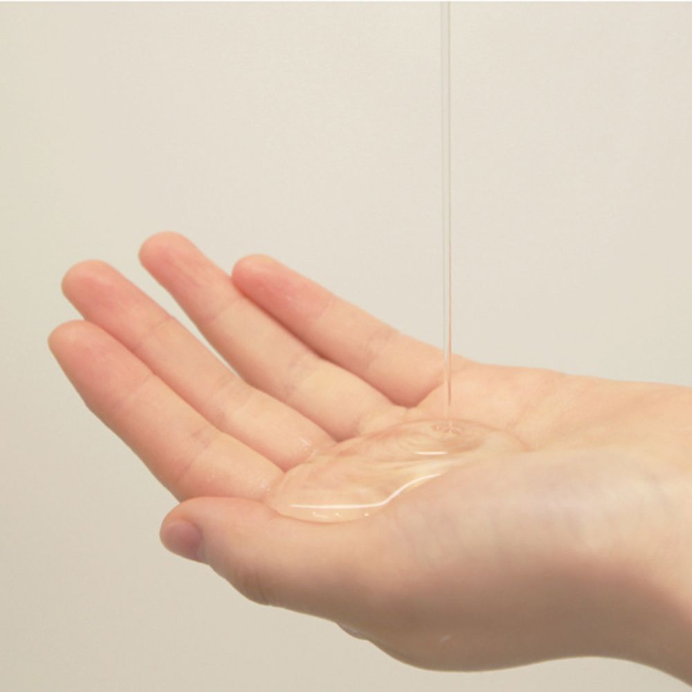 Main avec gel douche transparent. Le gel coule sur la paume. Peau claire.