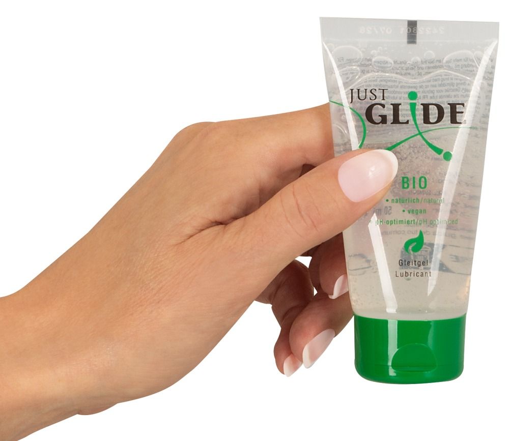 Une main tient un tube de lubrifiant avec un bouchon vert. Inscription : Just Glide Bio. Végétalien et pH optimisé.