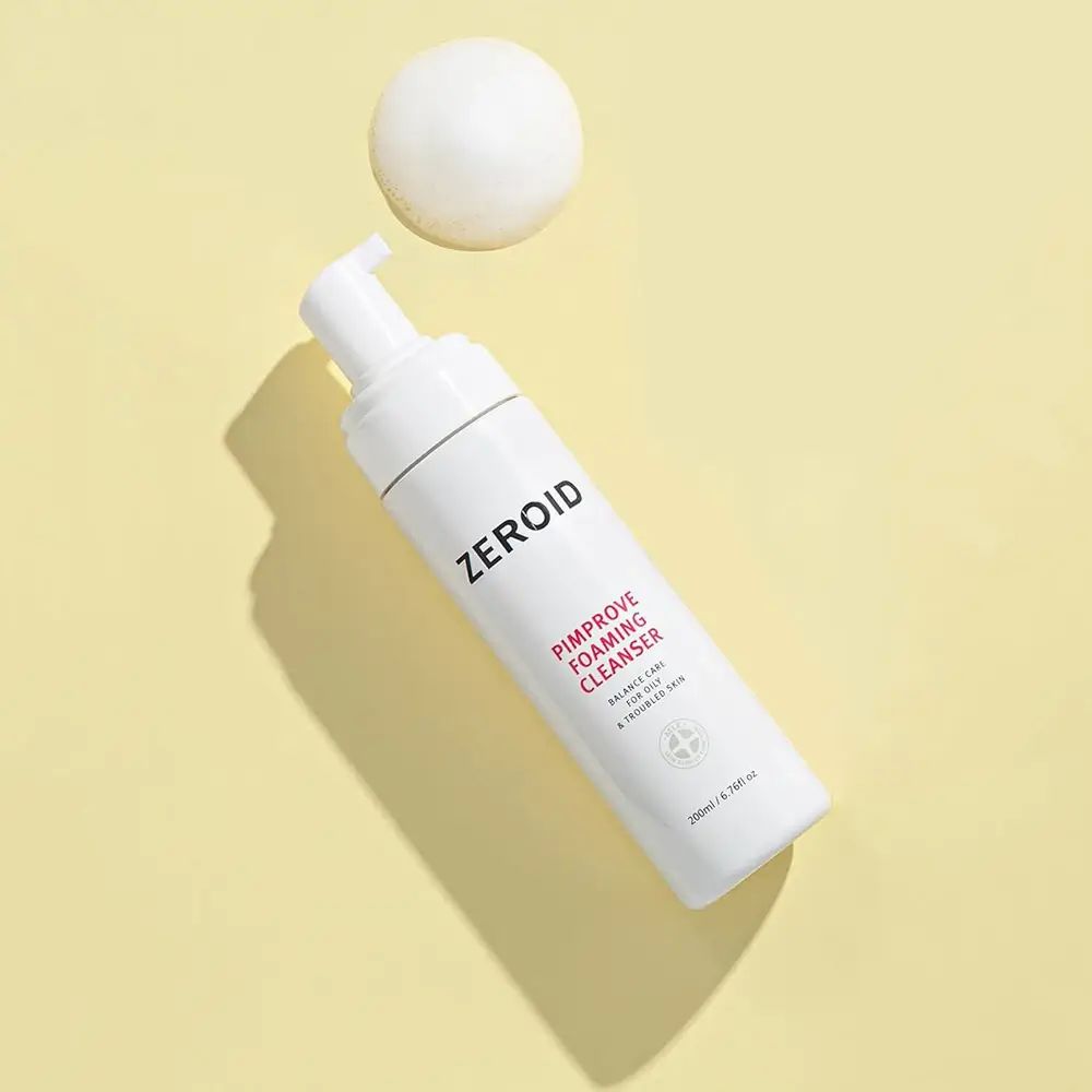 Flacon blanc ZEROID Pimprove Foaming Cleanser avec pompe. Nom du produit et texte. Sur fond jaune. Boule de mousse.