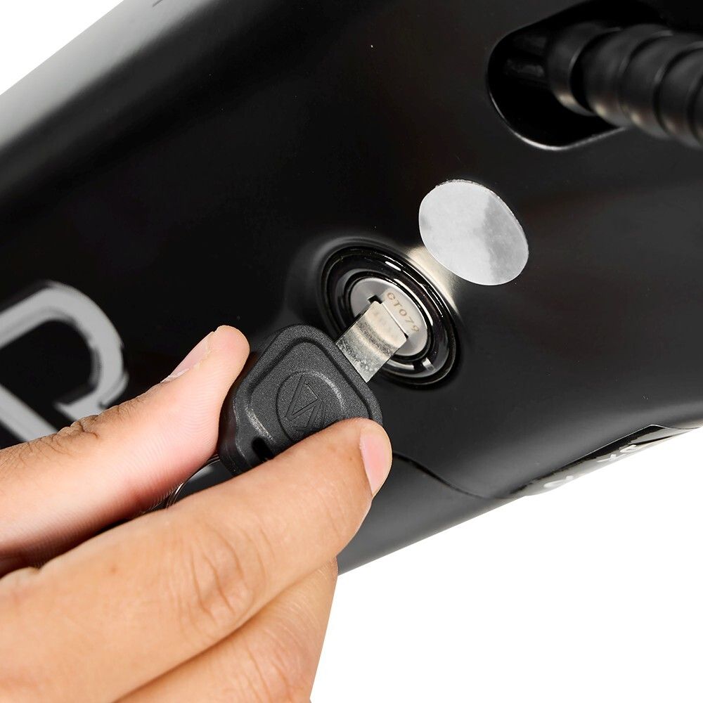 Close-up: sleutel wordt in het contactslot van een zwarte elektrische fiets gestoken. Zichtbaar: sleutel, slot, fietsframe.