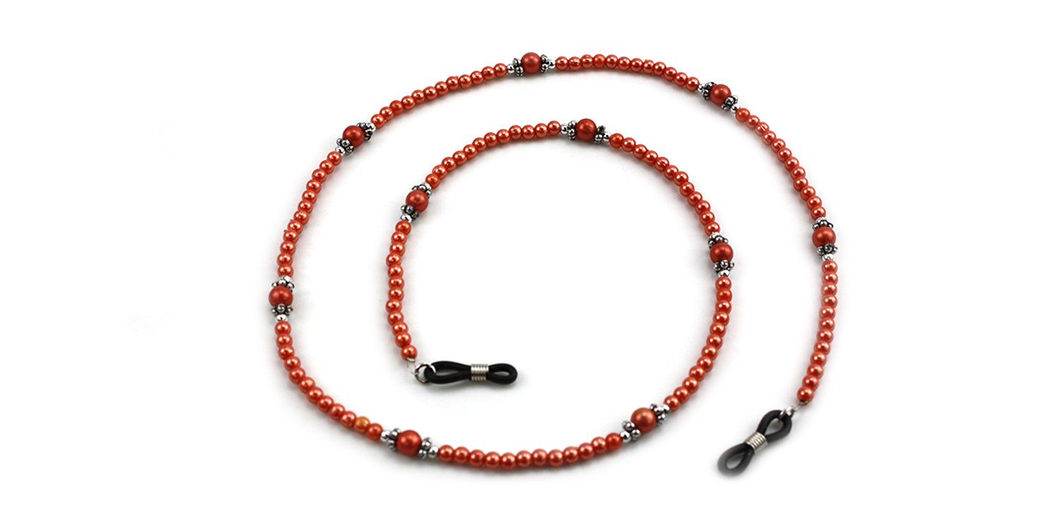 Cordon à lunettes avec perles rouges et éléments argentés. Attaches de lunettes noires aux extrémités. Sur fond blanc.