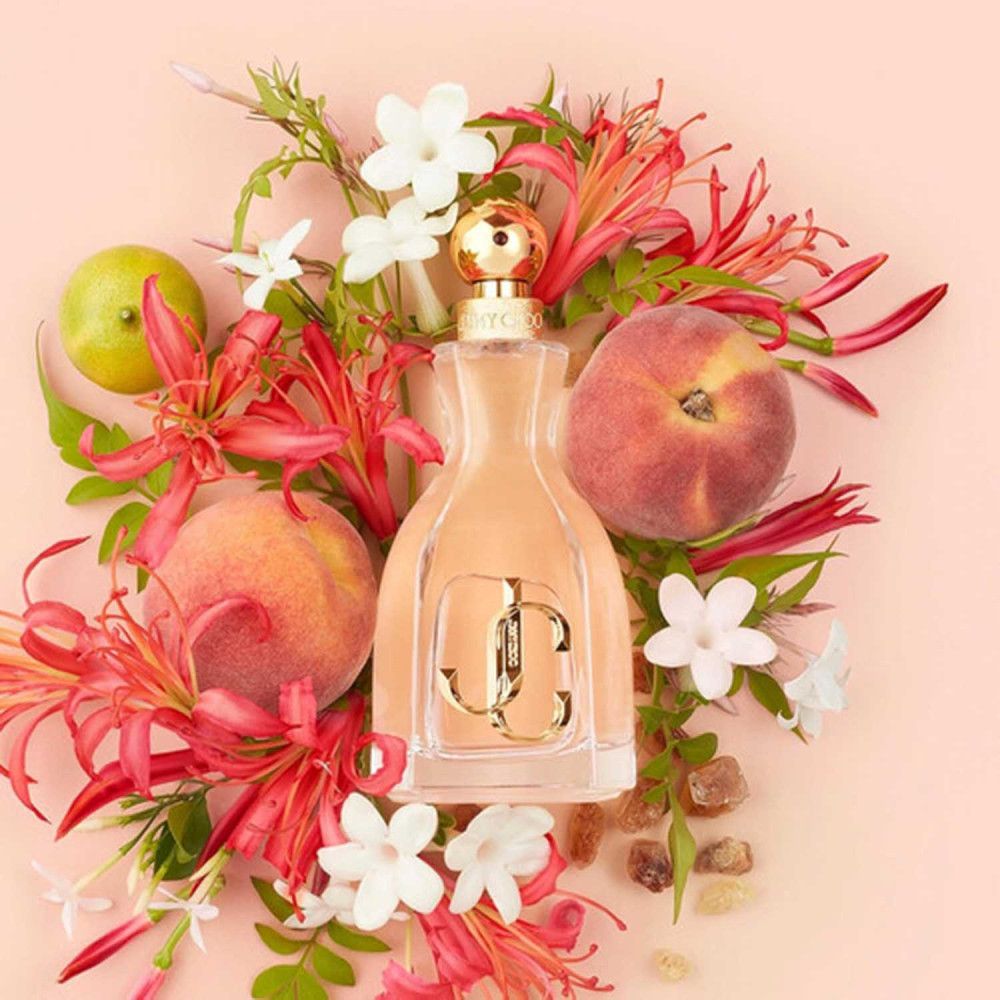 Flacon de parfum avec pêches, citron vert, fleurs et feuilles vertes.