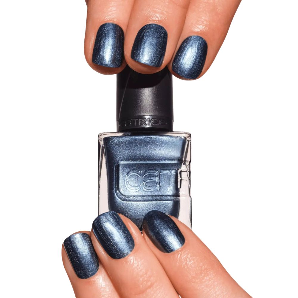 Mains avec ongles vernis et flacon de vernis. Couleur bleue. Marque Catrice visible.