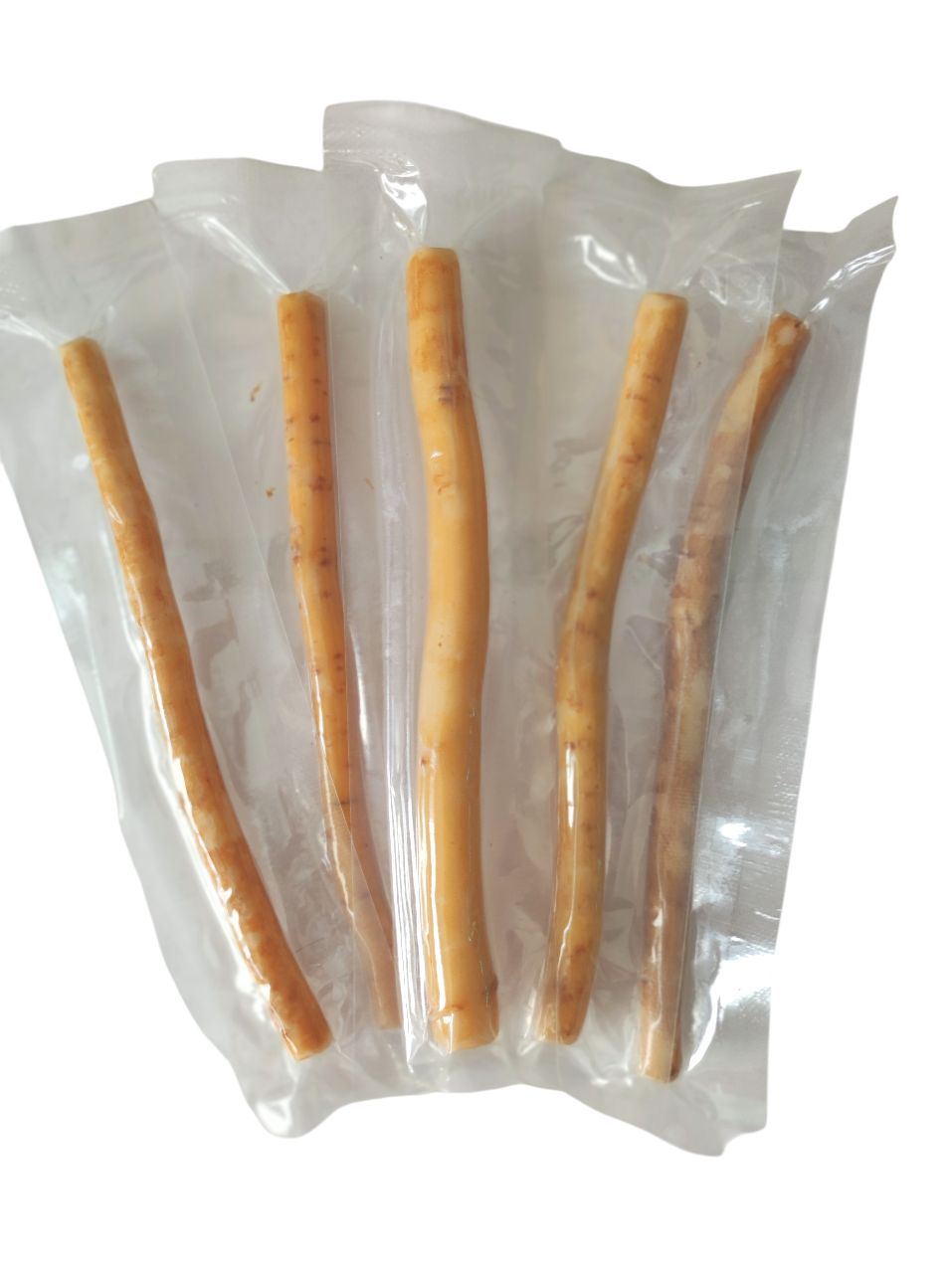 Verschillende miswak-sticks verpakt in folie. De sticks zijn lichtbruin en cilindrisch.