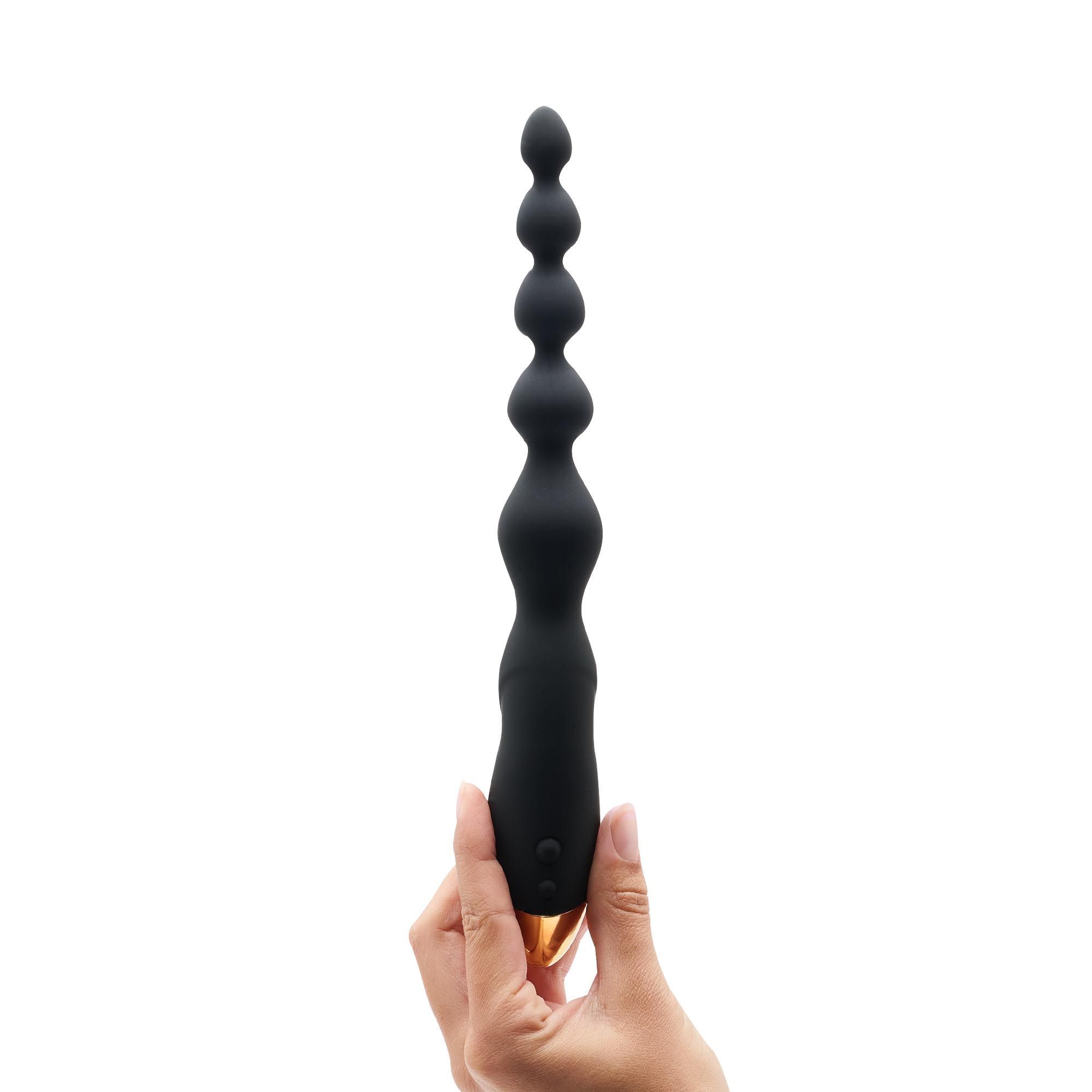 Zwarte vibrerende anale ketting met gouden uiteinde, vastgehouden door een hand. Meerdere ballen.