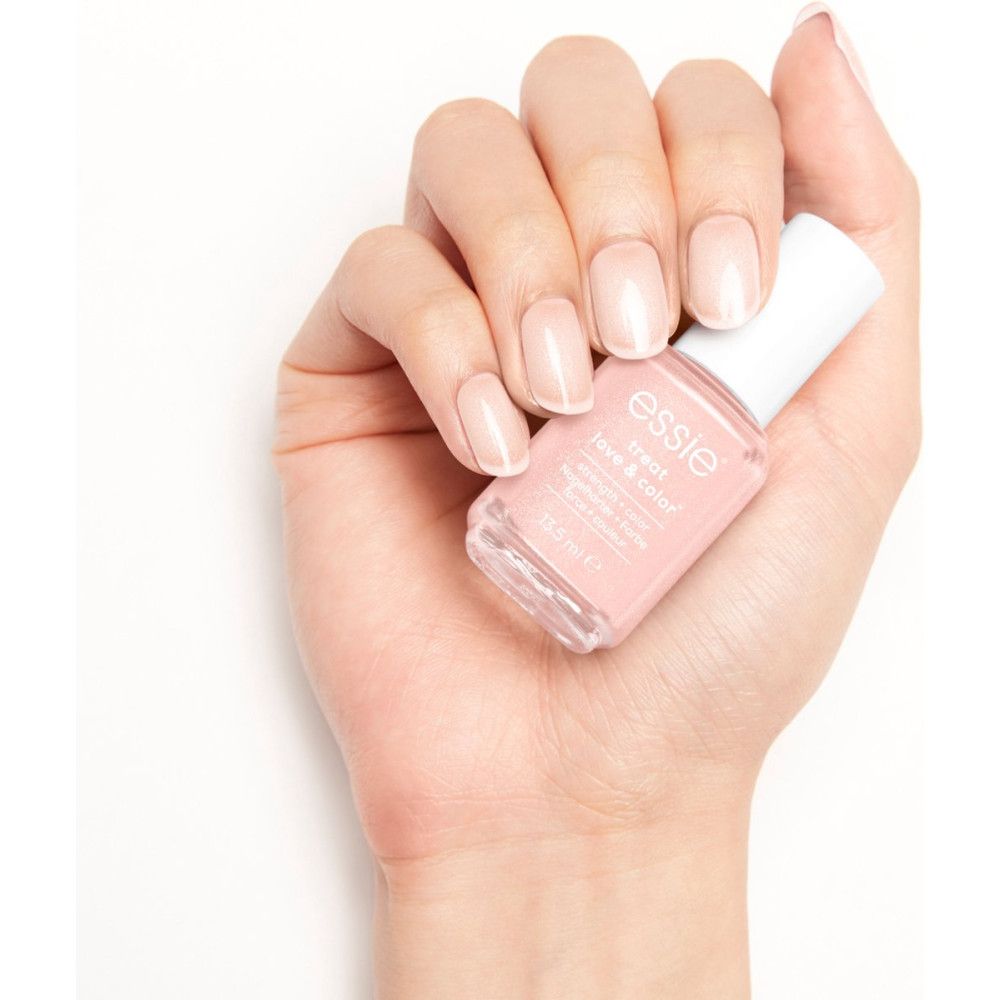 Main avec ongles vernis. Vernis à ongles Essie Treat Love & Color en rose. Fond blanc.