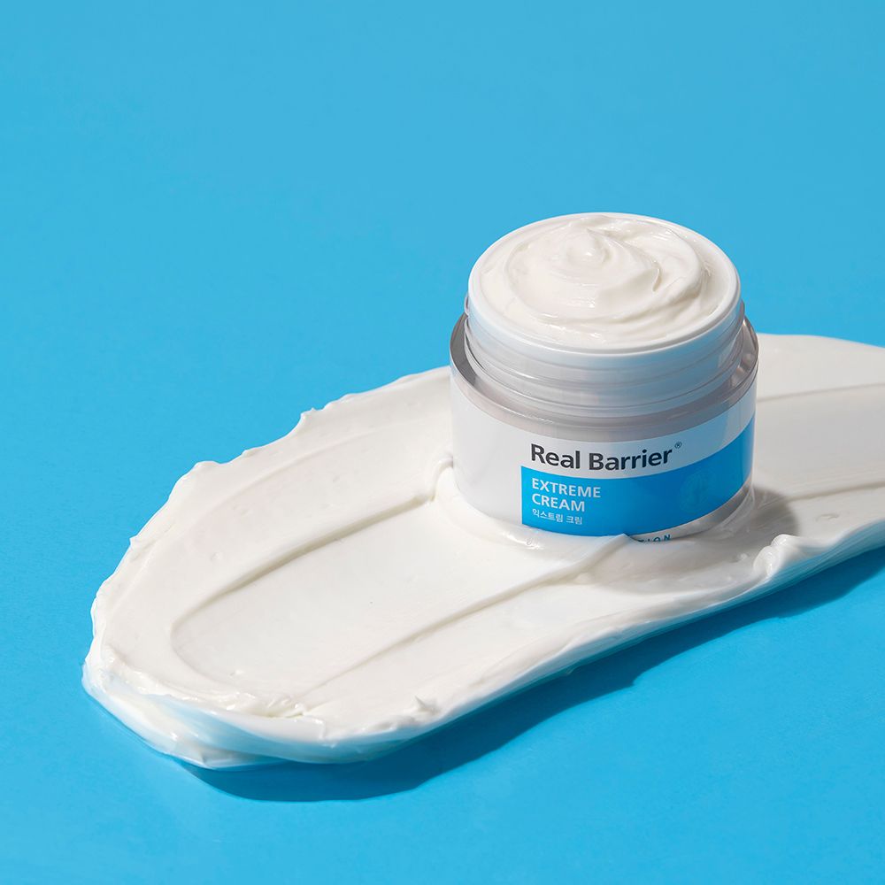 Open crèmepot op witte crèmevlek. Blauwe en witte kleurstelling. Achtergrond: lichtblauw.