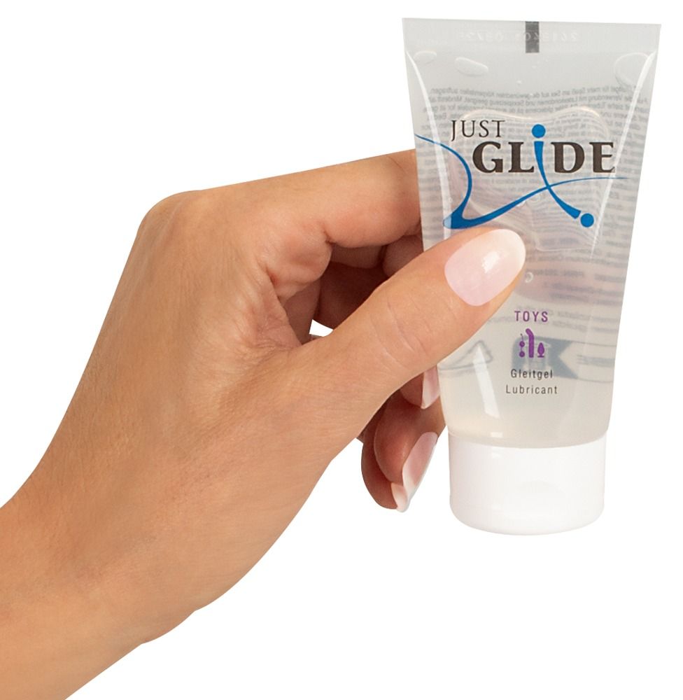 Main tenant un tube de lubrifiant Just Glide pour jouets.