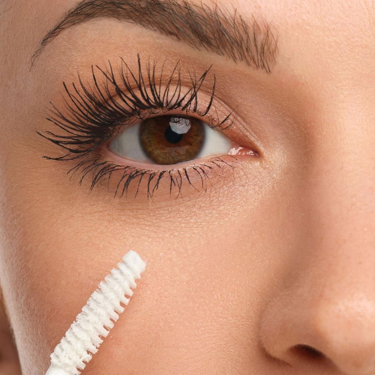 Oog met mascara op de wimpers. Borstel in de buurt van het oog.