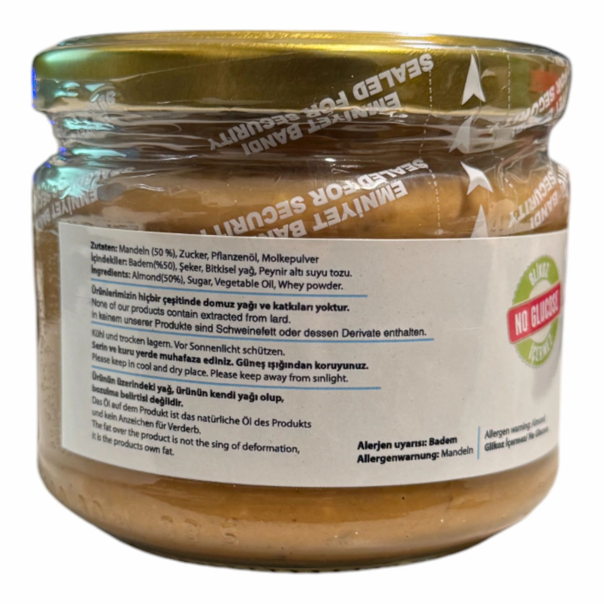 Achterkant van een pot amandelpasta. Tekst met ingrediënten, allergenenwaarschuwing en bewaaradvies. Zegel: Emniyet Bandi. Sticker: No Glucose.