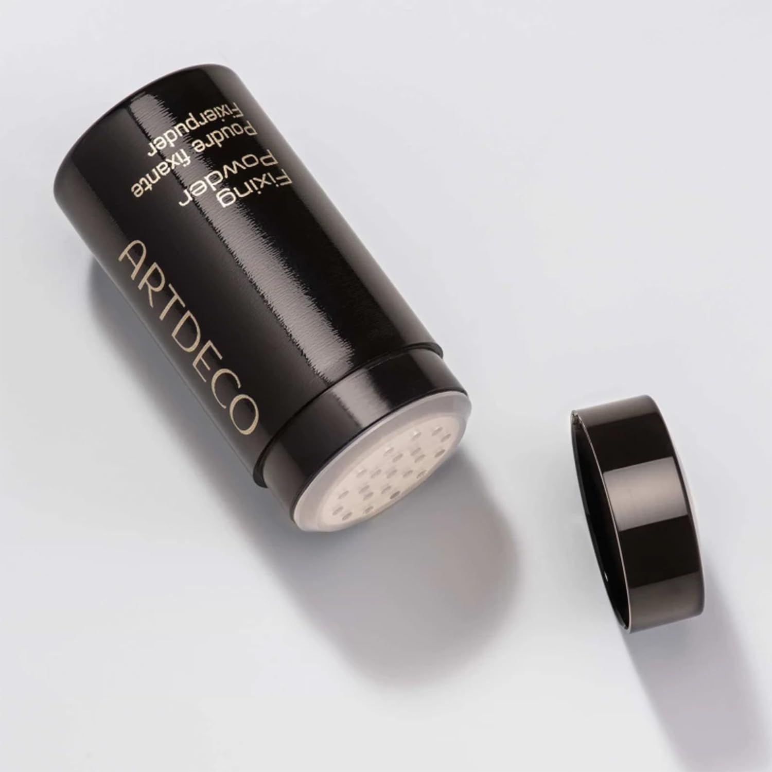 Zwarte Artdeco fixing powder container, open. Opschrift: Fixing Powder, Poudre fixante, Fixierpuder.