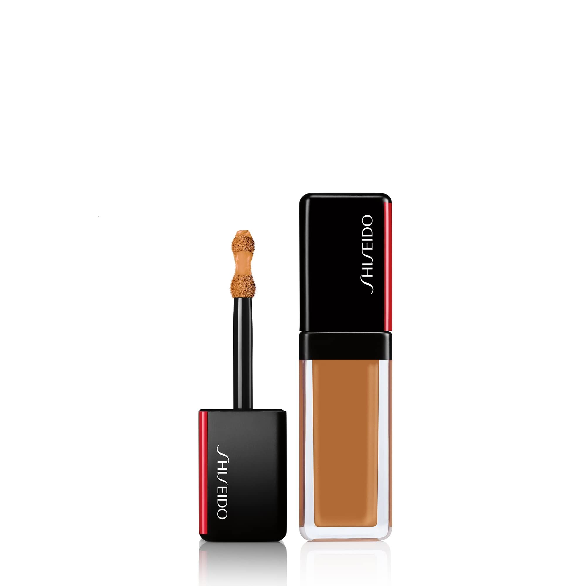 Flacon de correcteur avec applicateur. Bouchon noir avec bord rouge et logo Shiseido. Liquide brun visible.