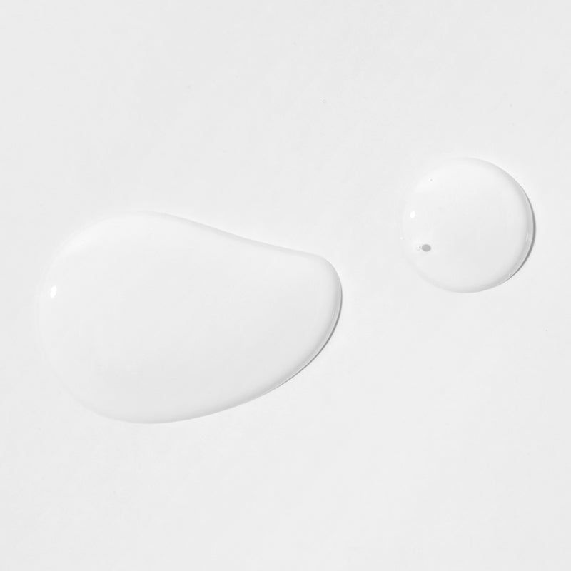 Twee druppels heldere vloeistof op witte achtergrond. Eén druppel langwerpig, de andere rond.