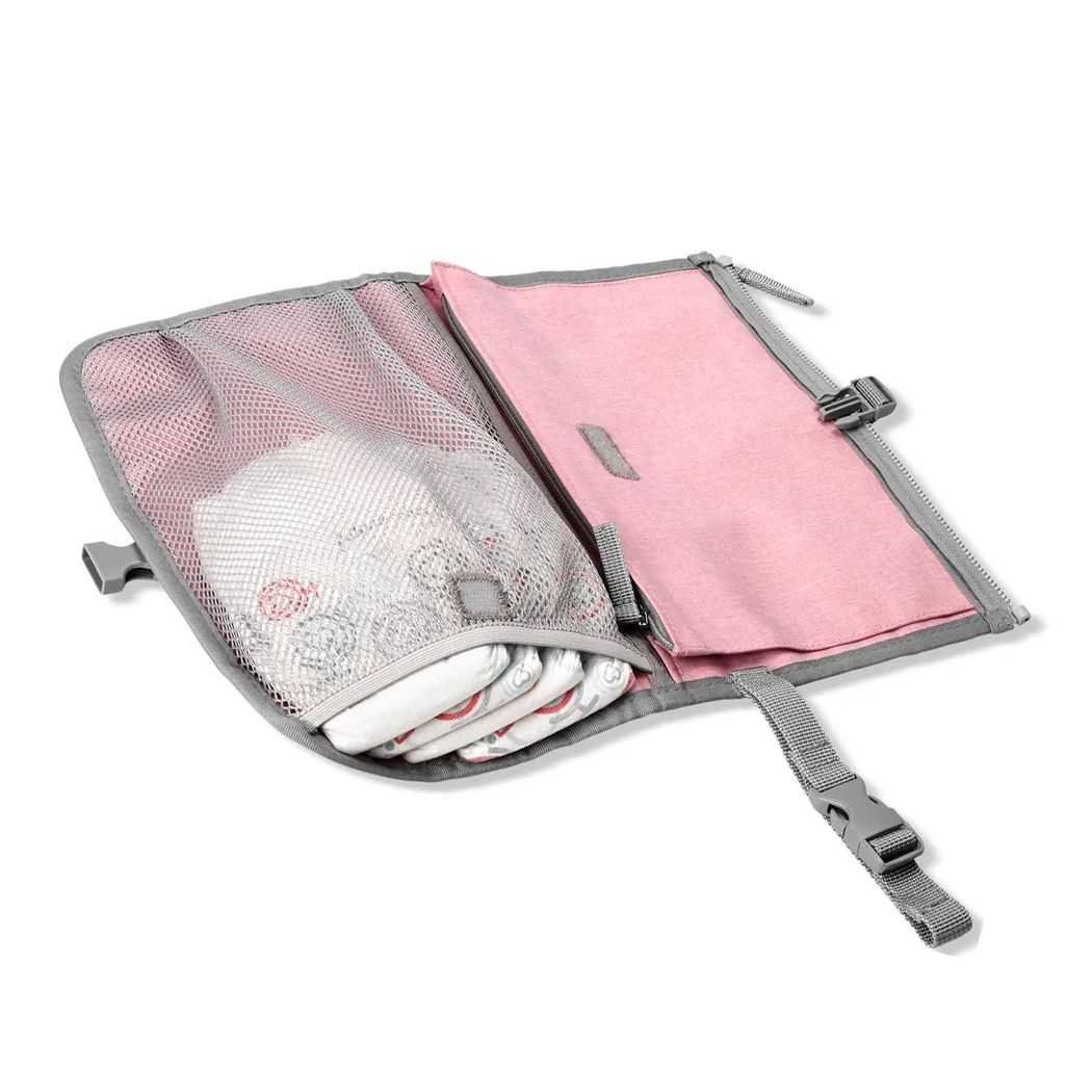 Roze aankleedkussen met grijze rand, open. Bevat luiers in een netvak en een roze gewatteerd oppervlak.