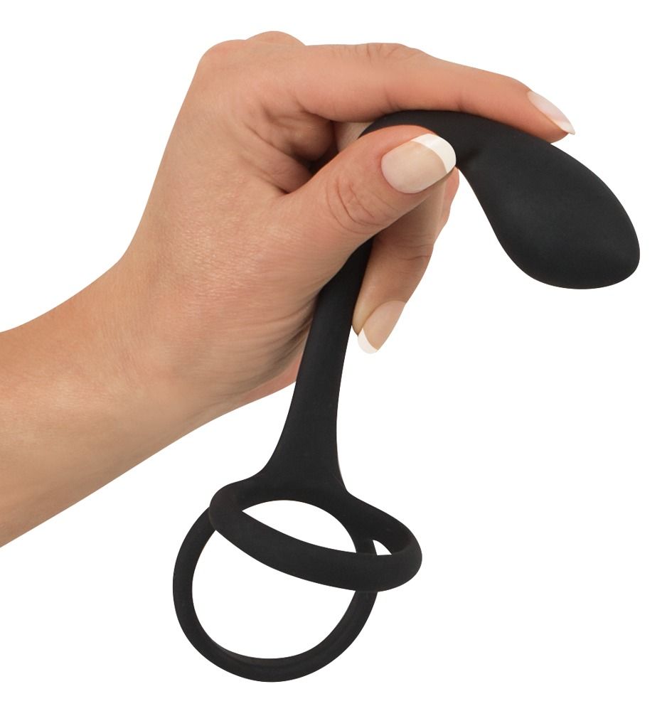 Main tenant un anneau de pénis/testicules noir avec plug anal en silicone.