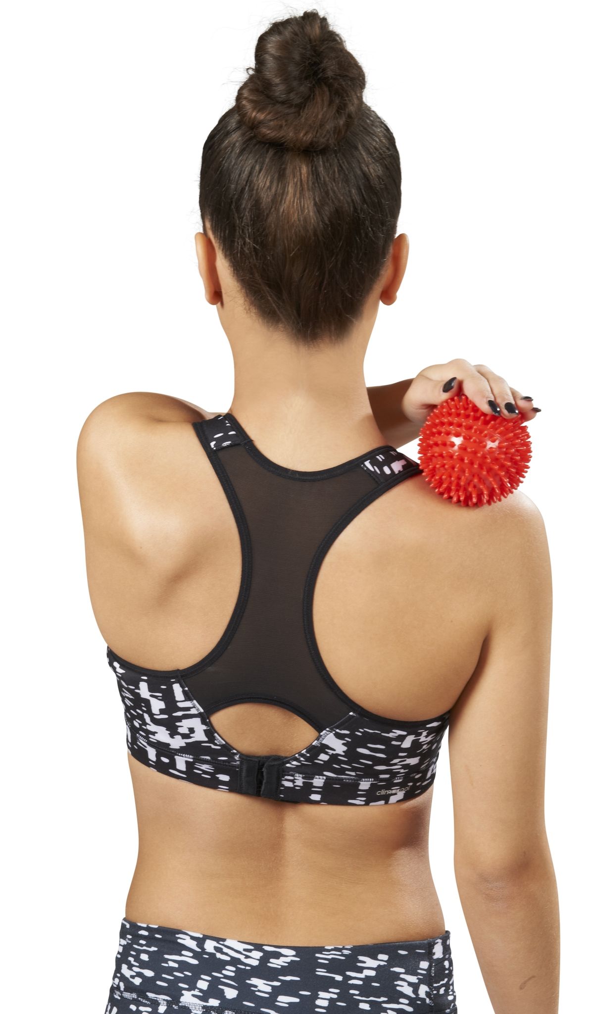 Vrouw houdt een rode, stekelige bal op haar schouder. Ze draagt sportkleding.