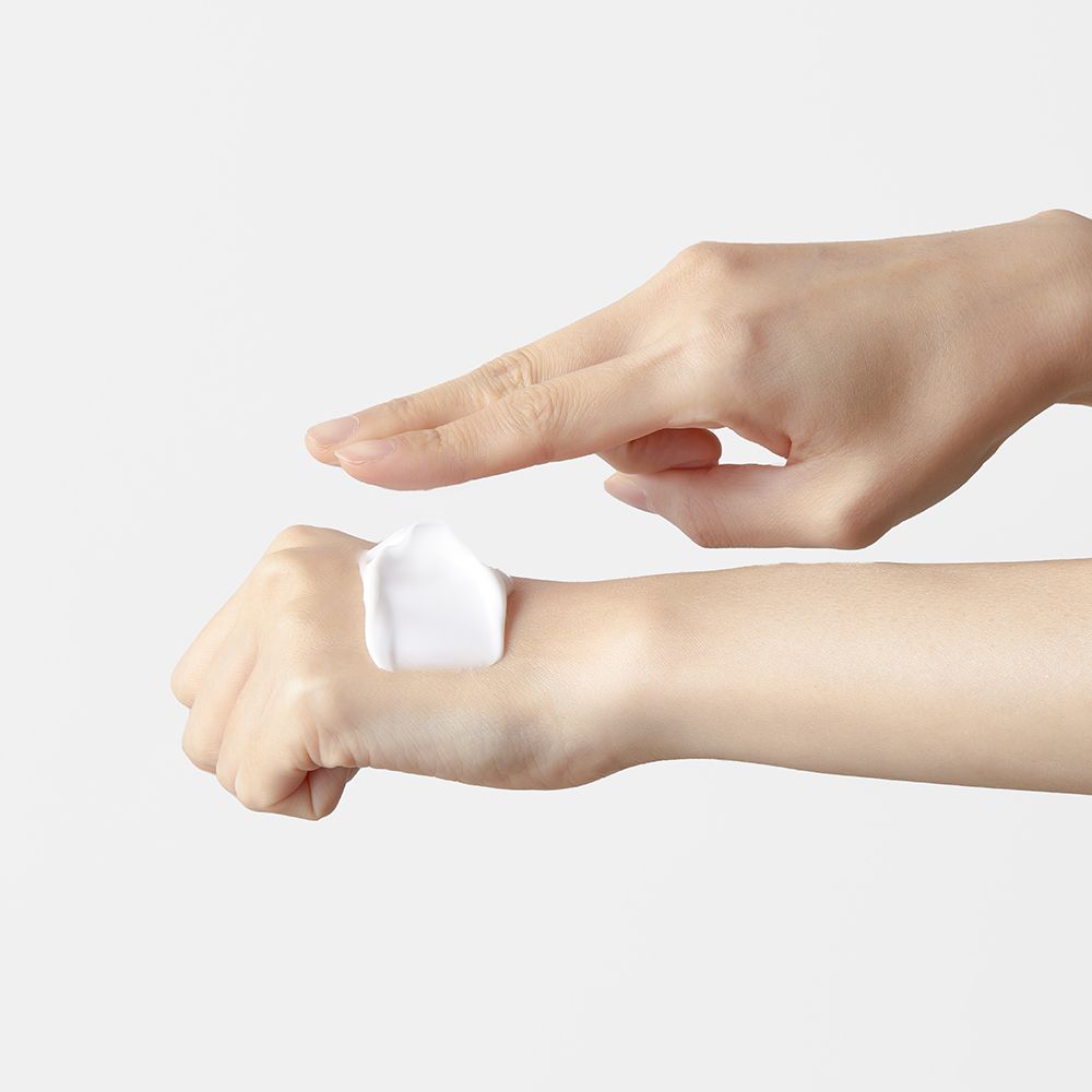 Mains avec crème. Une main applique de la crème. Crème blanche sur la peau.